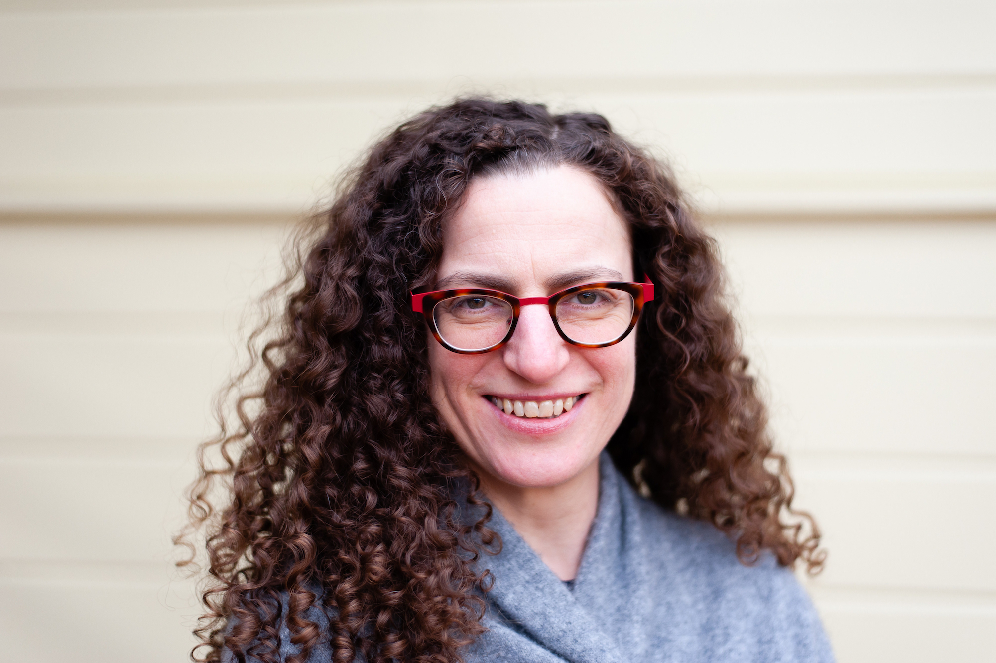 Picture of Amy Hofer, who is wearing glasses and has curly brown hair.